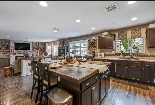 a kitchen with a stove a sink dishwasher a dining table and chairs with wooden floor