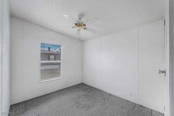 an empty room with windows and chandelier fan