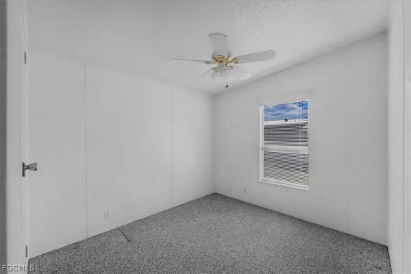 an empty room with windows and fan