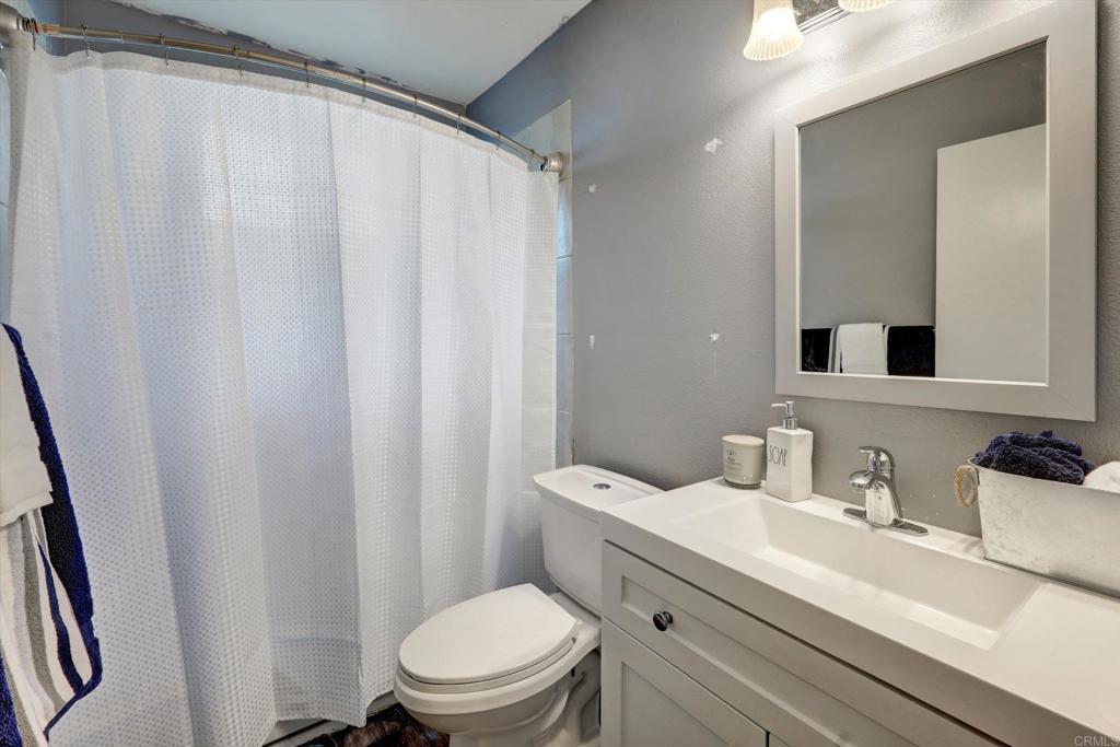 3011 Thunder Drive Oceanside, CA 92056 - Photo 23 of 28 a bathroom with a sink a toilet a mirror and shower curtain