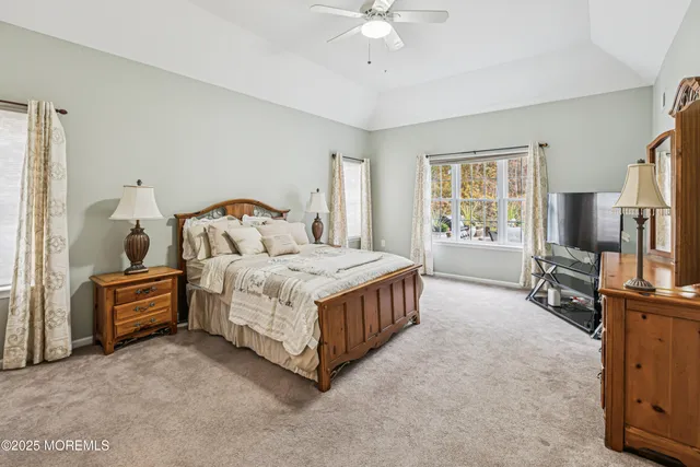 a bedroom with a bed flat screen tv and windows