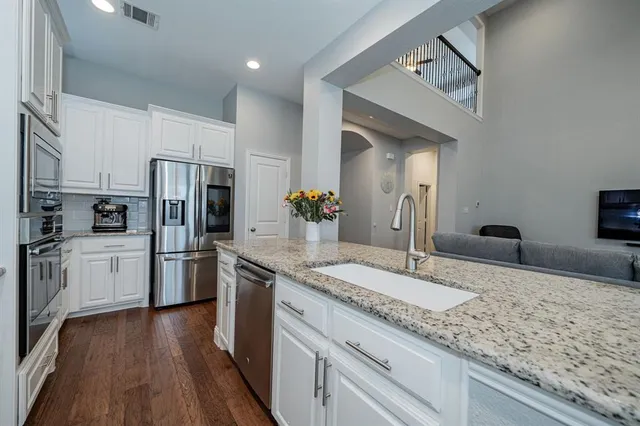 a large kitchen with stainless steel appliances granite countertop a lot of counter space and wooden floor