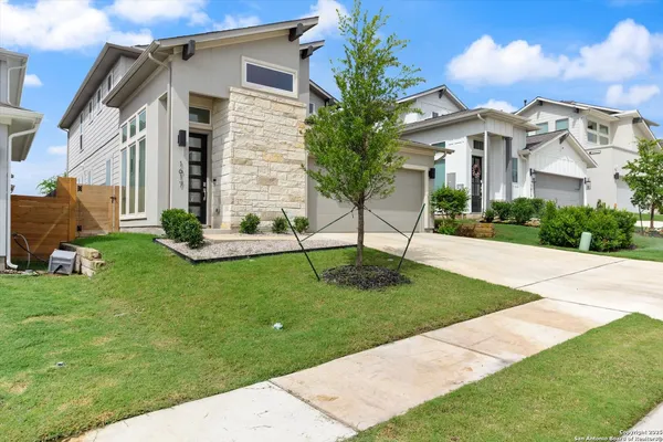 a view of a white house next to a yard with potted plants