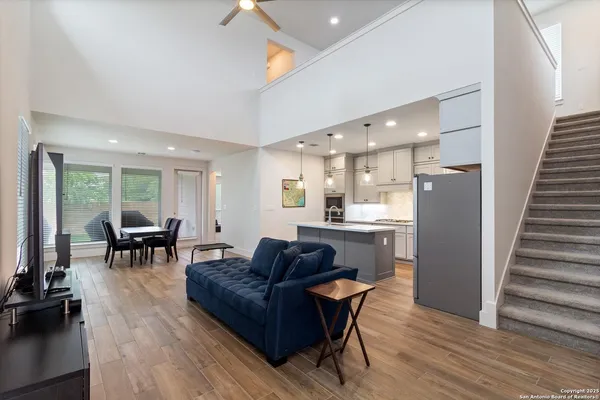 a living room with furniture and a dining table with wooden floor
