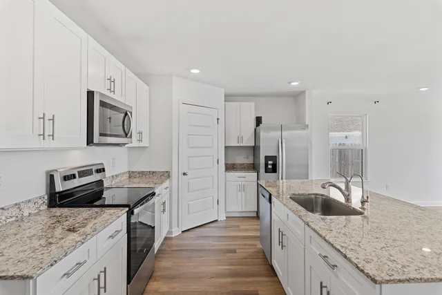 a kitchen with stainless steel appliances granite countertop a sink stove and refrigerator
