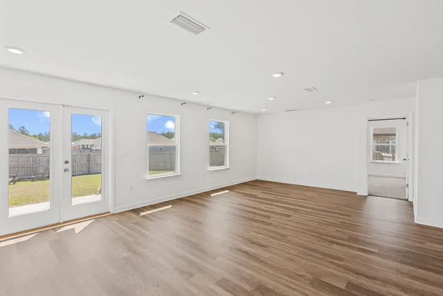 a view of an empty room with window and wooden floor