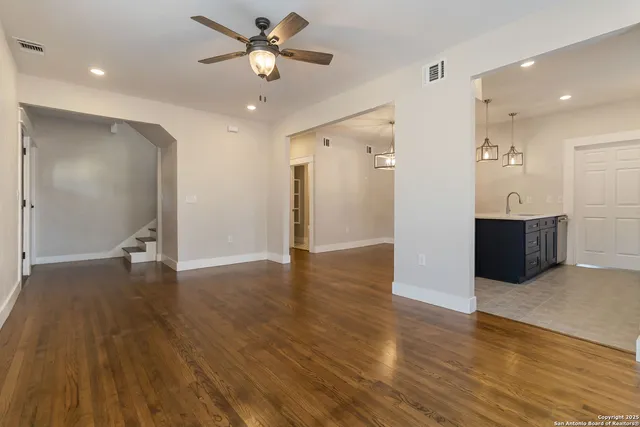 a view of empty room with wooden floor and ceiling fan