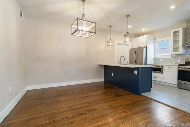 a kitchen with stainless steel appliances granite countertop a sink and a wooden floor