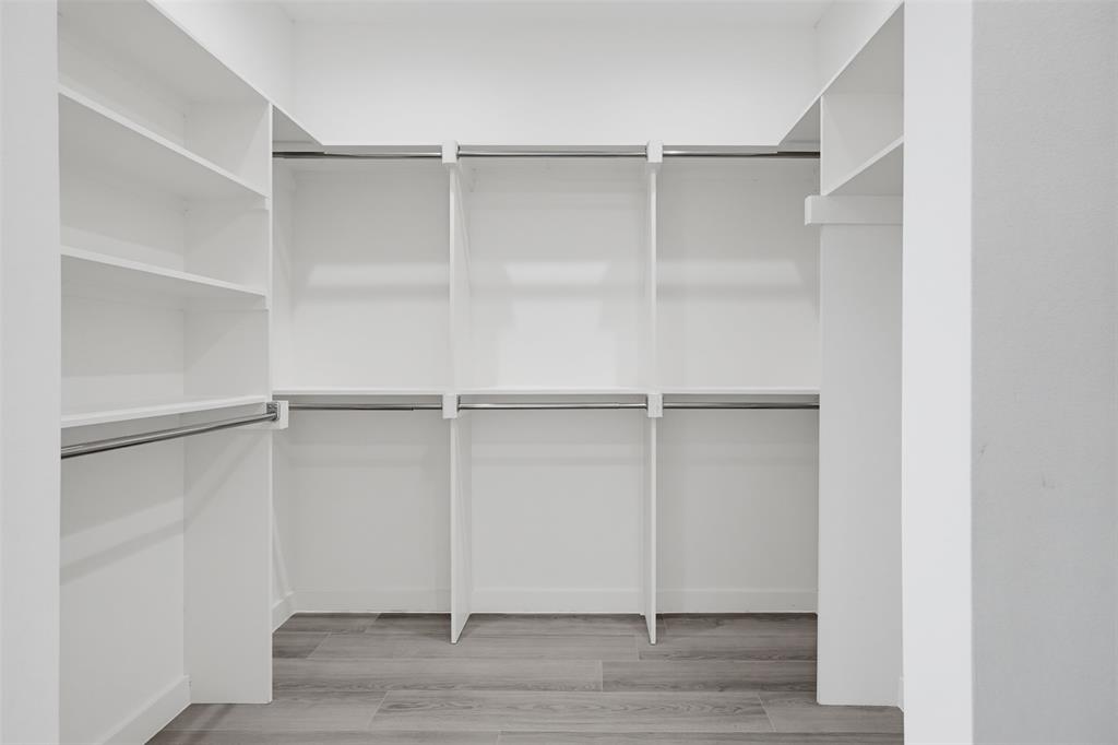 516 South O Connor Road Irving, TX 75060 - Photo 17 of 23 Walk-in closet featuring built-in white shelving, multiple hanging rods, and wood-finish flooring