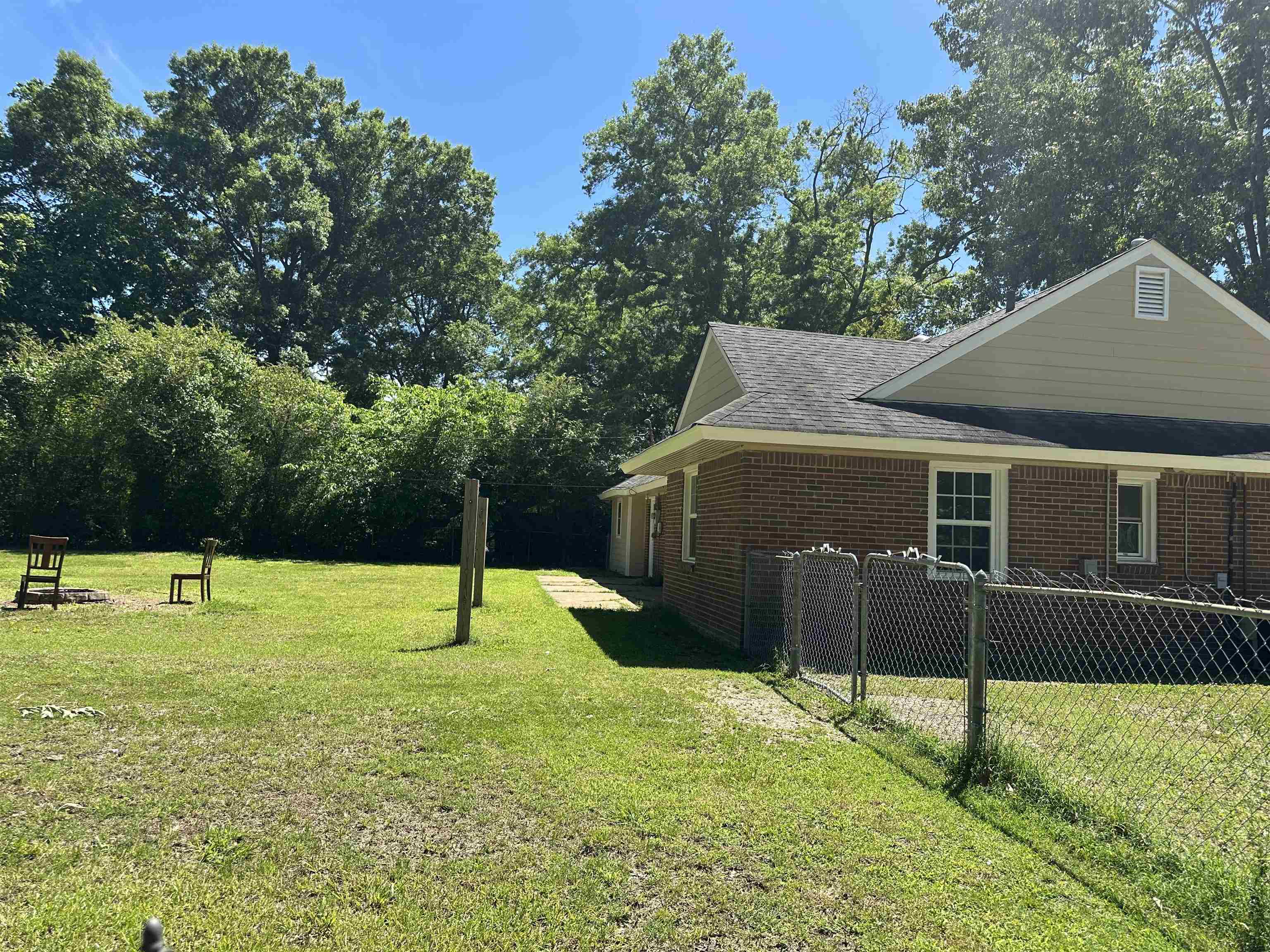 7874 Shamrock Road Millington, TN 38053 - Photo 17 of 17 Expansive rear yard featuring mature perimeter trees, a lush green lawn, and a partial chain-link fence