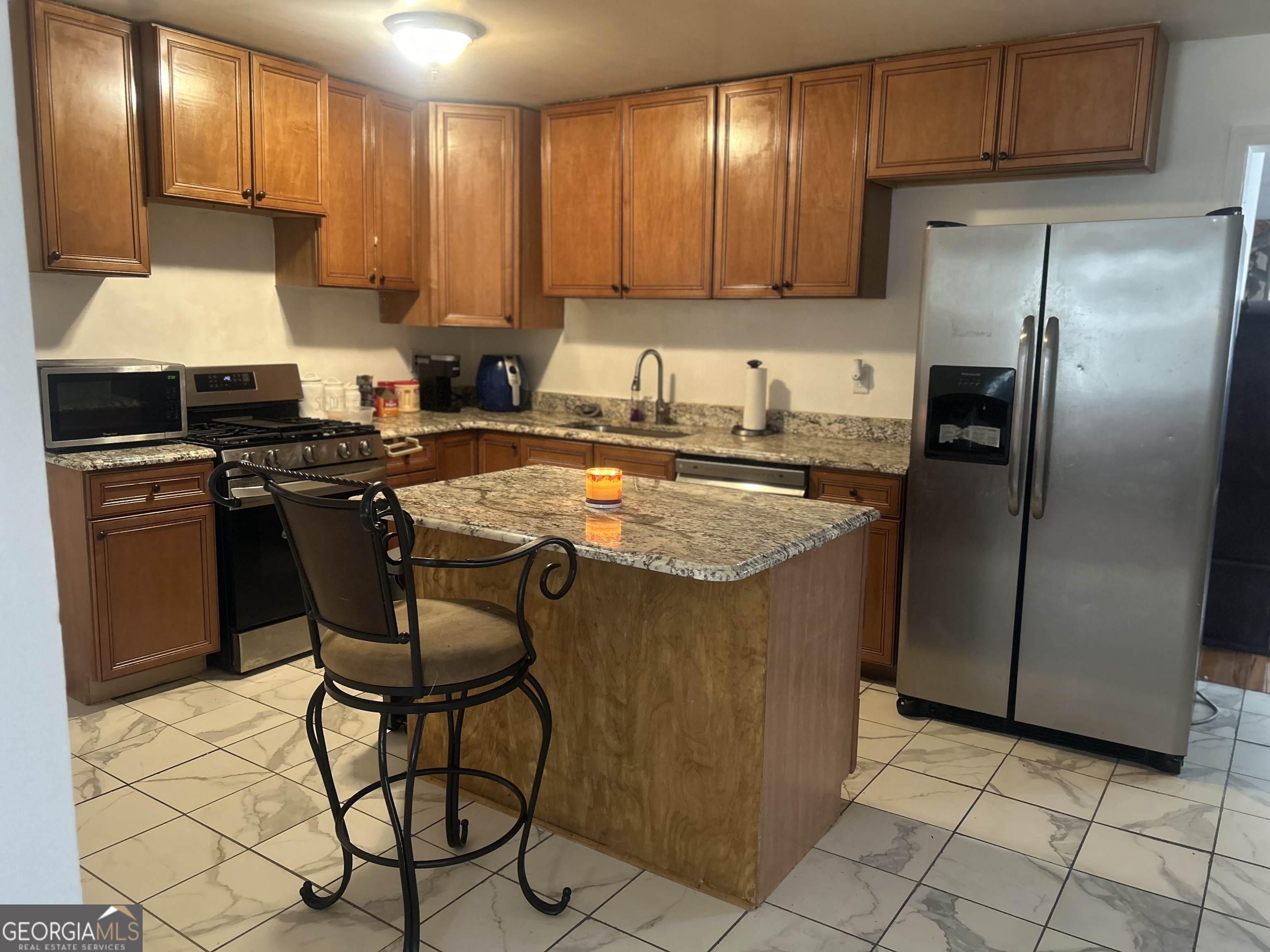 1406 Canterbury Road Griffin, GA 30223 - Photo 12 of 26 a kitchen with stainless steel appliances granite countertop a stove a refrigerator a sink a dining table and chairs