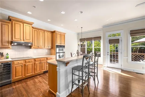 a kitchen with stainless steel appliances granite countertop wooden floor a dining table and chairs