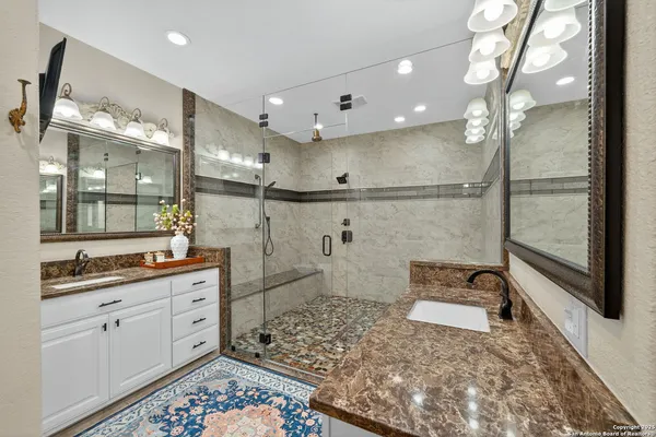 a bathroom with a double vanity sink a toilet a mirror and shower