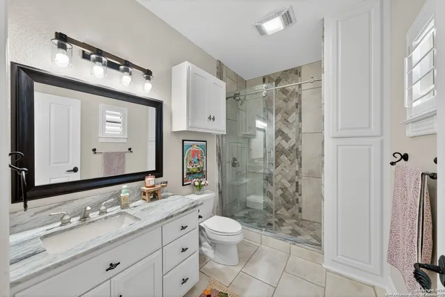 a bathroom with a granite countertop sink toilet a mirror a vanity and shower