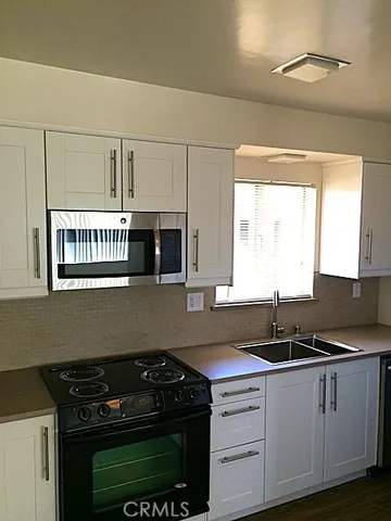 a kitchen with granite countertop a sink a stove and cabinets