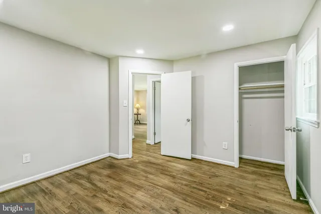 a view of an empty room with wooden floor and closet