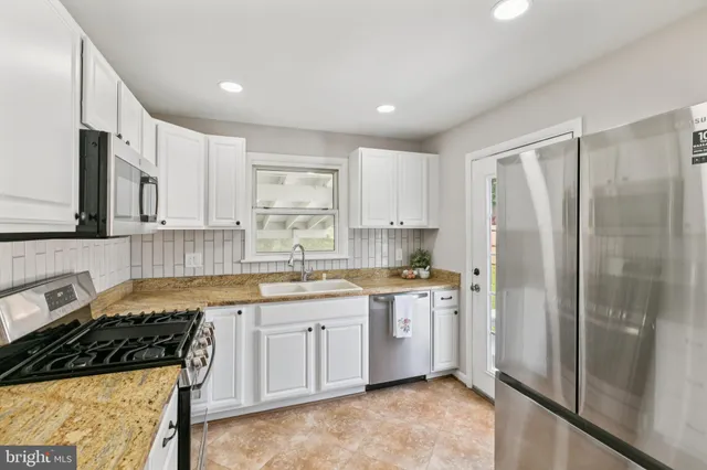 a kitchen with stainless steel appliances granite countertop a stove a sink and a refrigerator