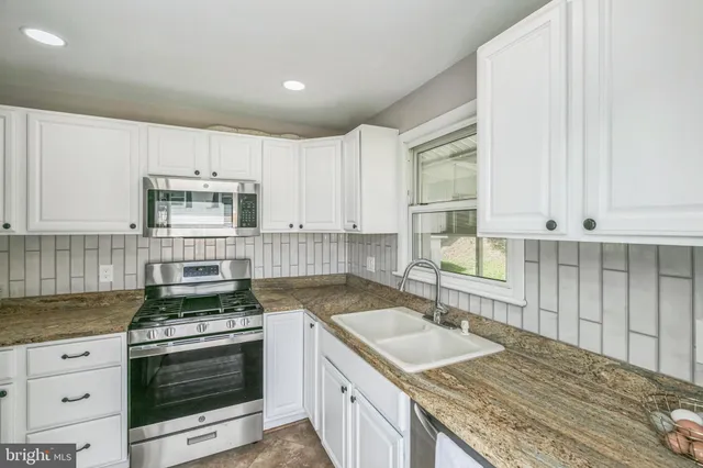 a kitchen with granite countertop a sink stove and cabinets