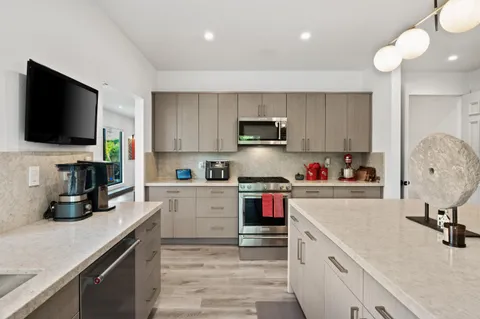a large kitchen with kitchen island a large window a sink and stainless steel appliances