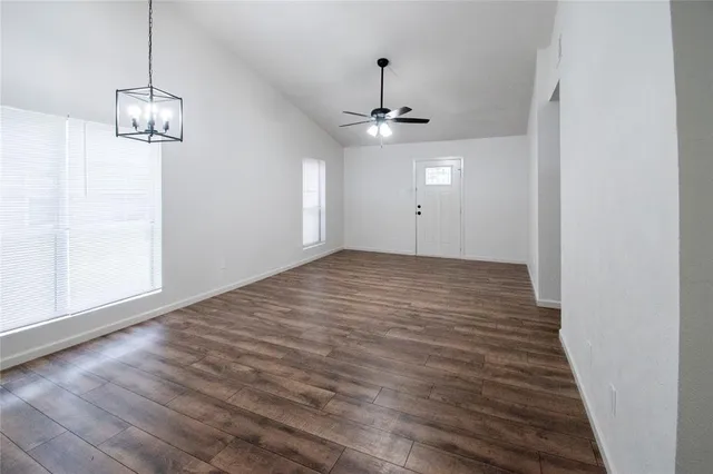 a view of empty room with wooden floor and chandelier