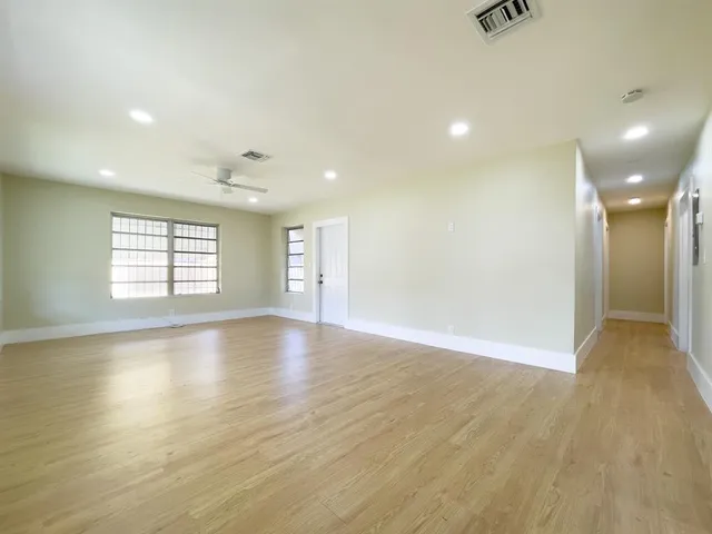 an empty room with wooden floor and windows