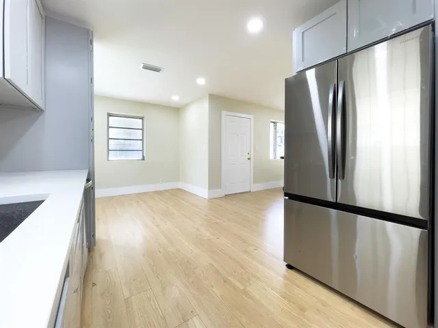 a view of a kitchen with a refrigerator and wooden floor