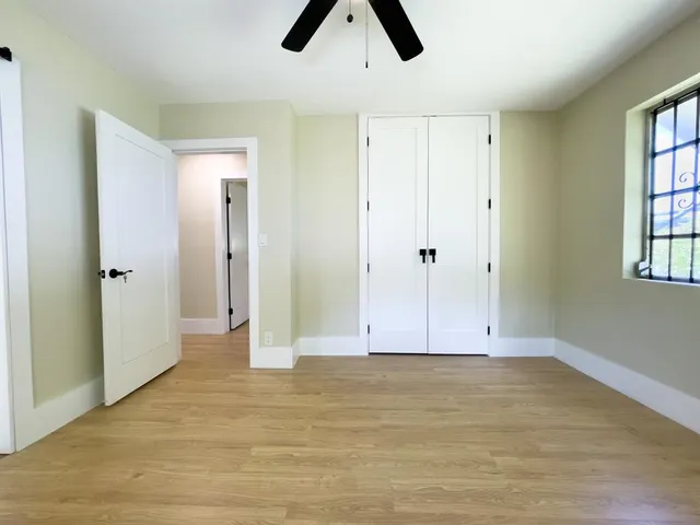 a view of an empty room with window and chandelier fan