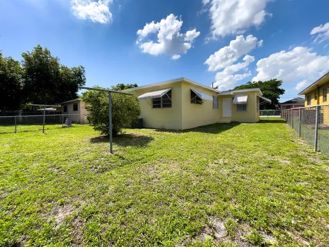a yellow house with a yard and a large tree