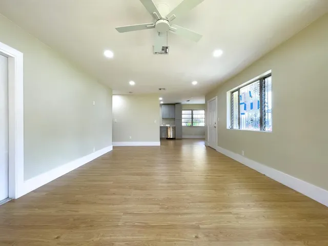 a view of an empty room with window and wooden floor