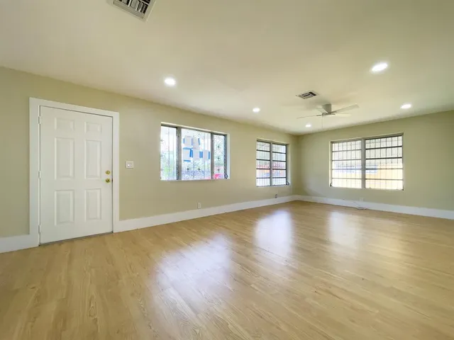 an empty room with wooden floor and windows