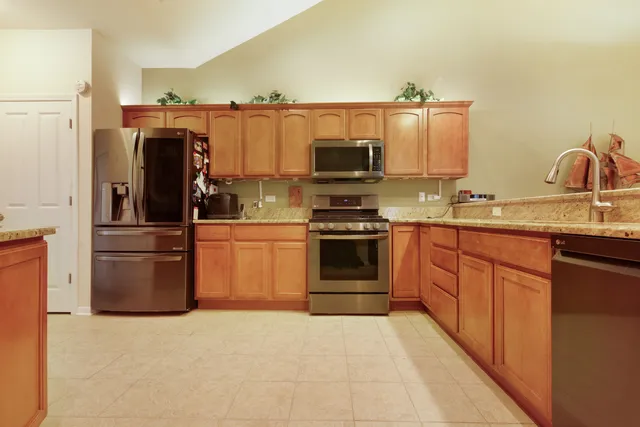 a kitchen with stainless steel appliances granite countertop a refrigerator stove and sink