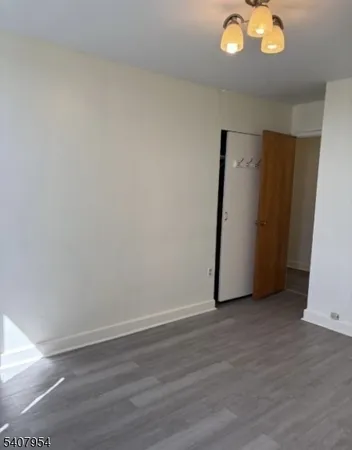 a view of an empty room with wooden floor and window