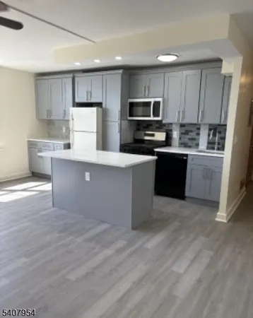 a large kitchen with stainless steel appliances a sink a stove a refrigerator and cabinets