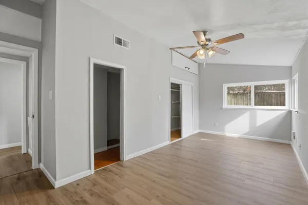 a view of an empty room with wooden floor and a window