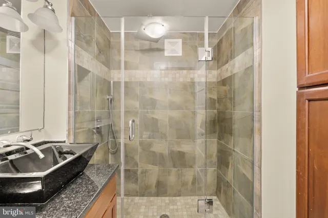 a bathroom with a granite countertop shower a sink and dishwasher