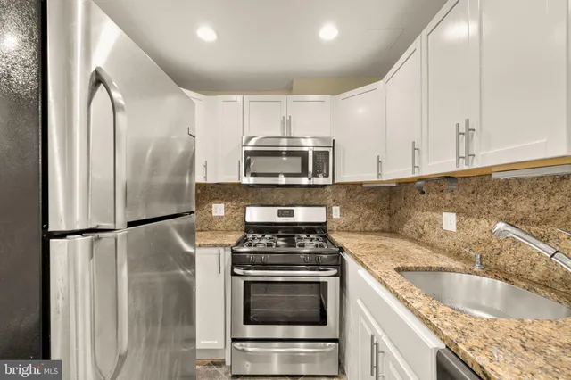 a kitchen with granite countertop a refrigerator stove and microwave