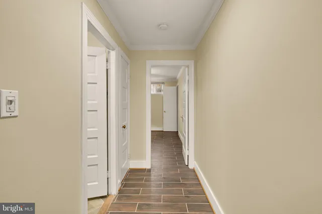 a view of a hallway with wooden floor and a bathroom