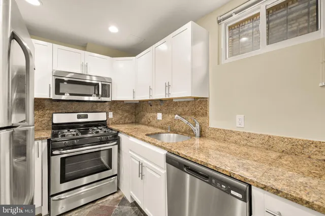 a kitchen with granite countertop a sink stove and microwave