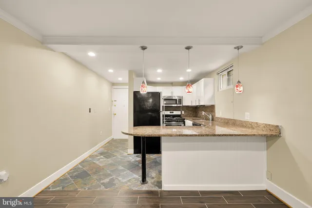 a room with kitchen island a sink and a refrigerator