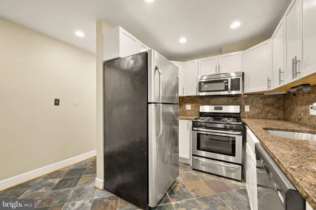 a kitchen with stainless steel appliances granite countertop a refrigerator a stove and a sink