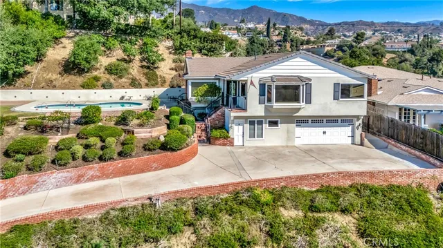 a view of a white house with a large windows and a yard with plants