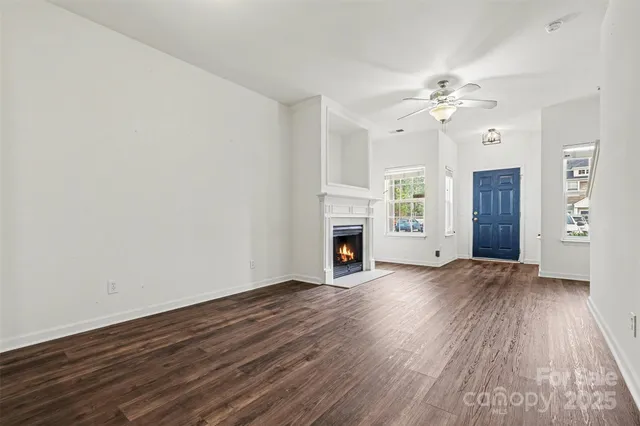 an empty room with wooden floor fireplace and windows
