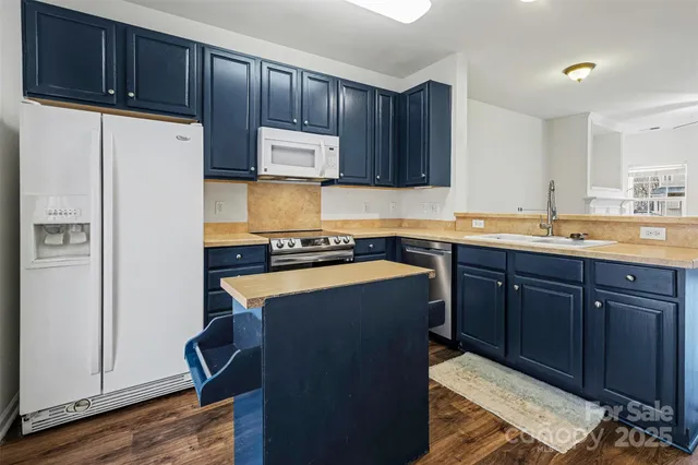 a kitchen with stainless steel appliances granite countertop a refrigerator a sink dishwasher and wooden cabinets with wooden floor