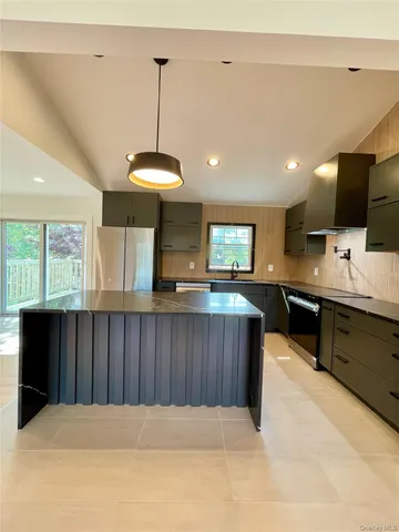 a kitchen with a refrigerator and a television