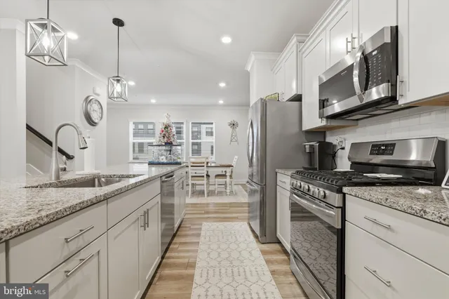 a kitchen with stainless steel appliances granite countertop a sink a stove top oven and refrigerator