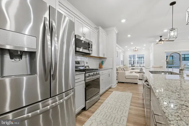 a kitchen with stainless steel appliances granite countertop a refrigerator a stove and a sink