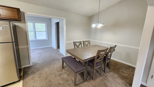 a view of a dining room with furniture and a refrigerator