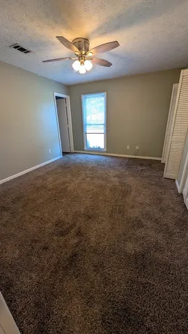 en empty room with windows and fan