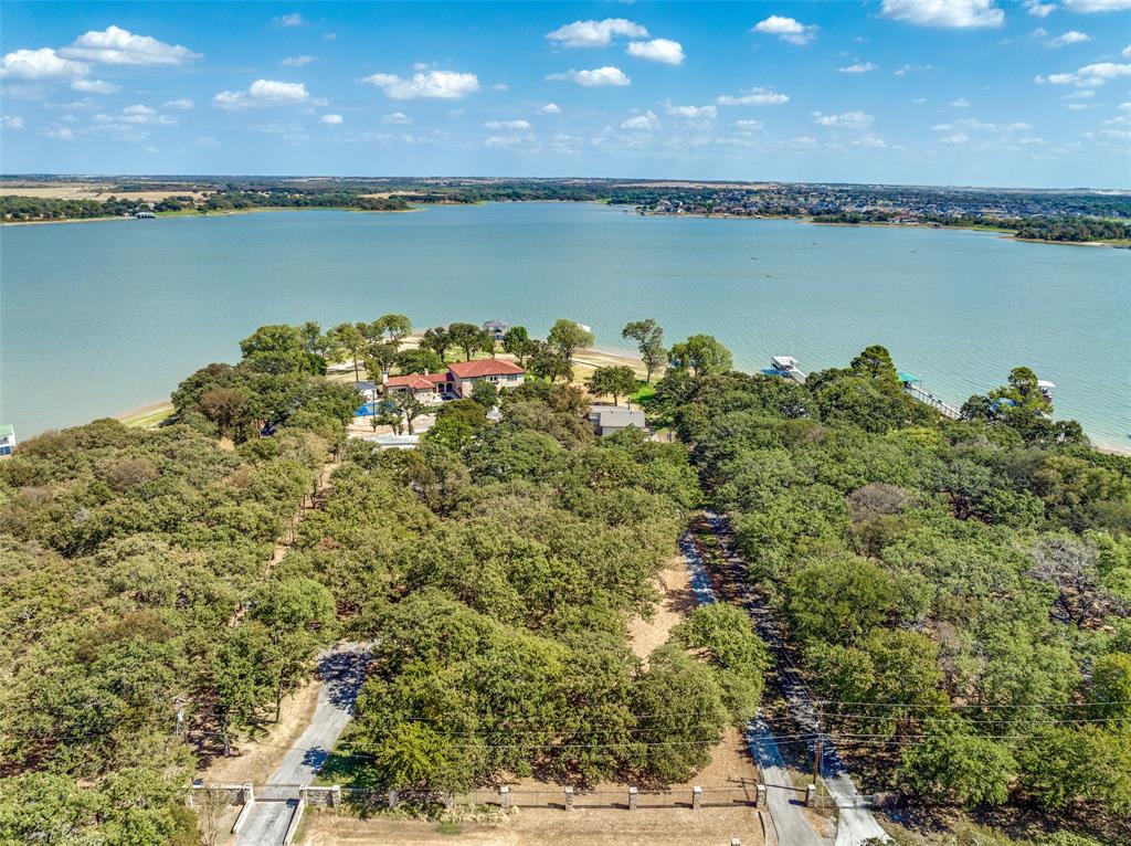 12960 Gantt Road East Azle, TX 76020 - Photo 1 of 26 Expansive waterfront property featuring mature tree coverage, a residential structure with a red tile roof, and a private boat dock