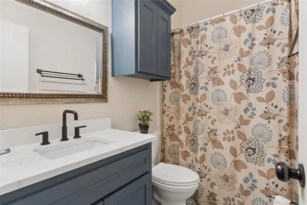 a bathroom with a granite countertop sink a toilet and a mirror